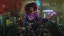 A pretty black woman with an afro wearing a purple shirt with long black sleeves sits in a messy basement with a gun levitating bullets with purple energy in her right hand