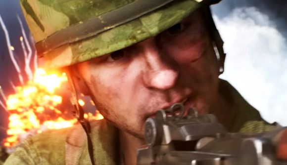Battlefield V sets new Steam player count record - A soldier wearing green camo and holding a rifle. An explosion goes off behind him.