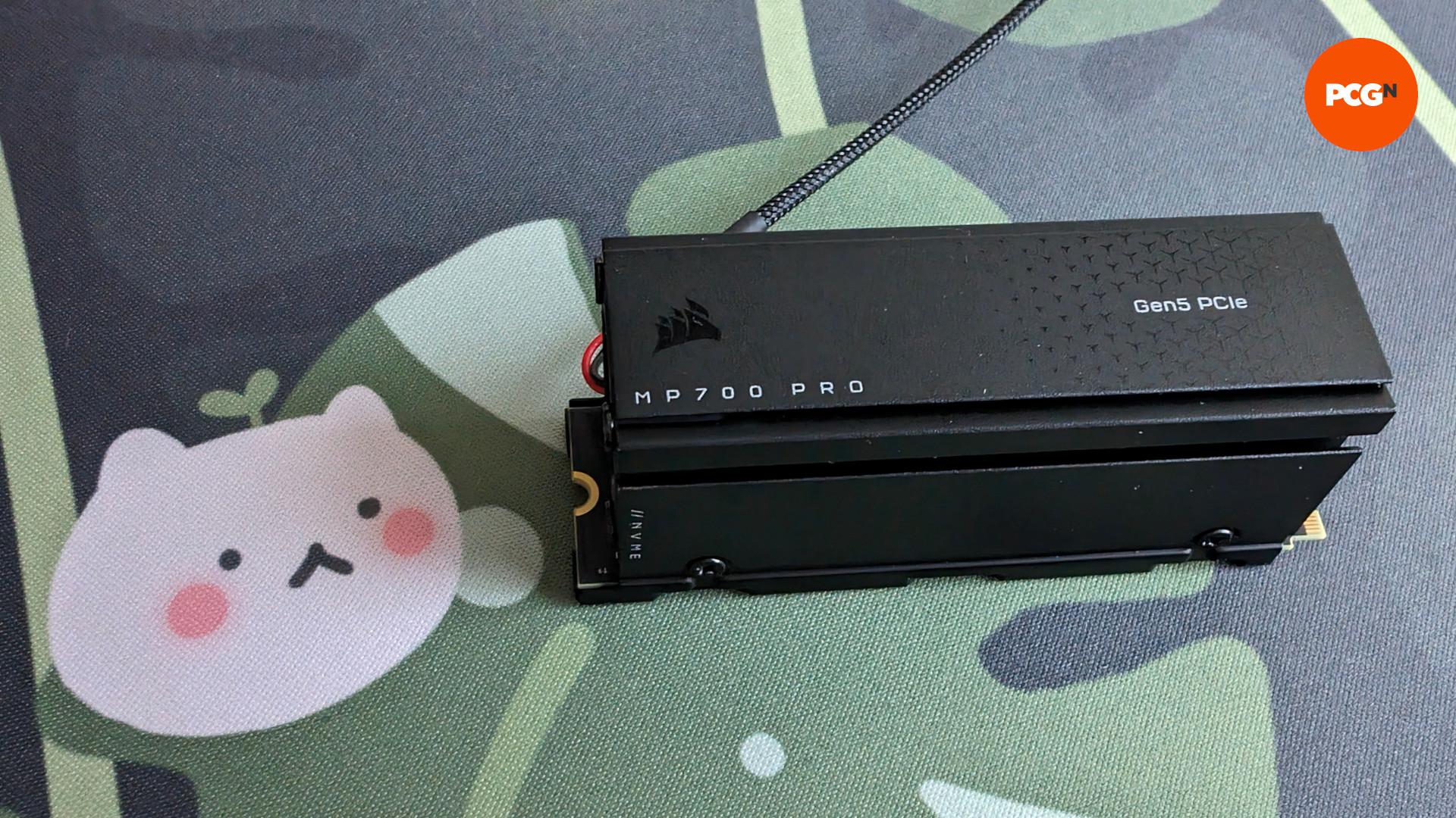 The Corsair MP700 Pro against a leafy background, featuring a small white cat-like character (left)
