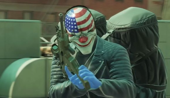 Payday 3 update free: a man reloading an AR on a rooftop, with a duffle bag slung over his shoulder a black leather jacket on, wearing a clown mask with the American flag on it