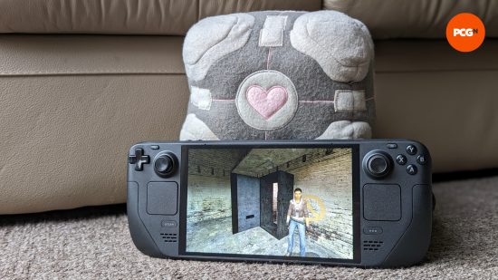 The Steam Deck OLED resting against a Companion Cube plushie