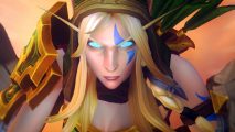 A blond elf woman with glowing blue eyes and a blue marking on her face glares into the camera