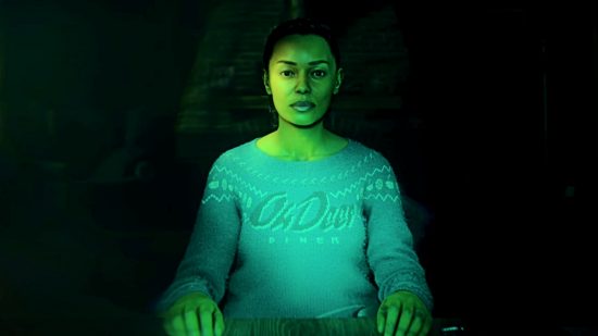Alan Wake 2 The Final Draft: A woman sitting under green lighting at a wooden table with her hands before her stares ahead, her expression blank