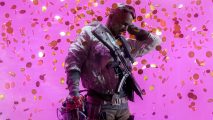 Black man in combat gear with a gun on his chest standing in front of pink background.