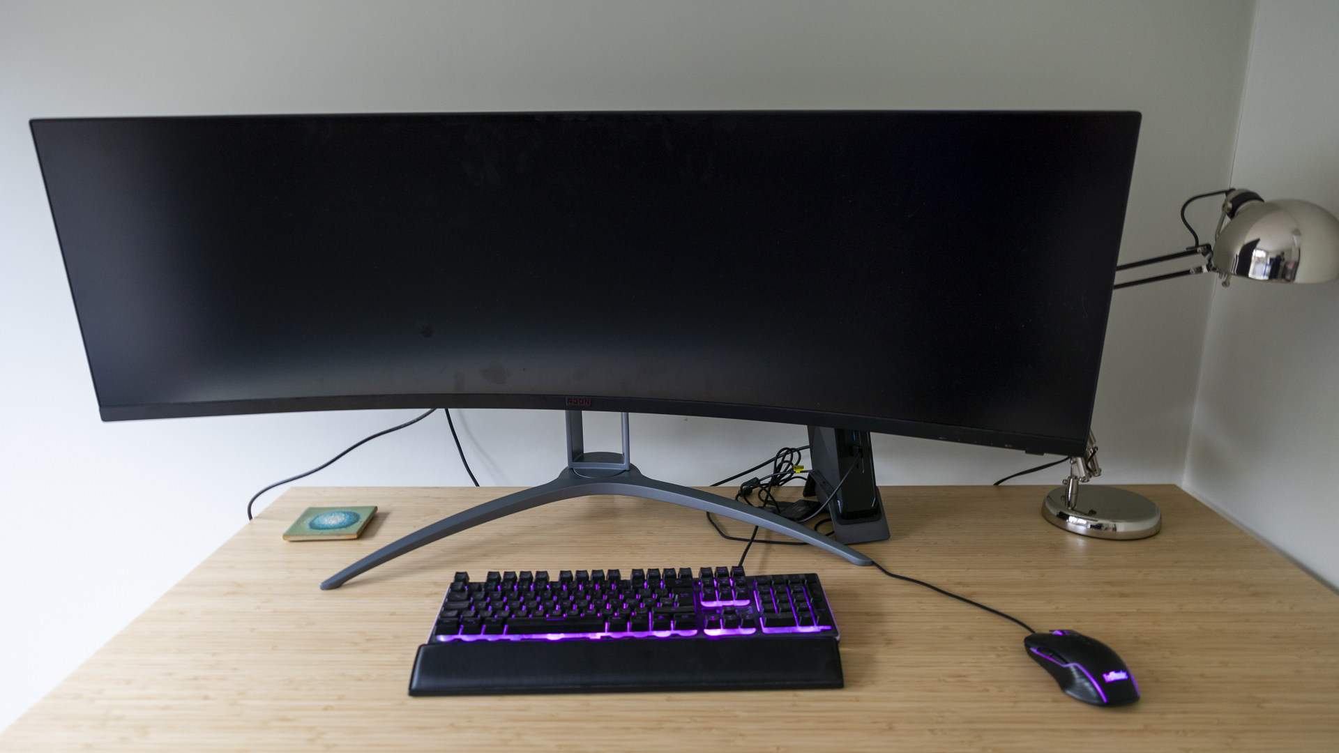 The AOC Agon AG493UCX2 monitor on a bamboo desk with the screen off