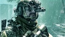 A man wearing military gear and goggles, looking right while rain pours onto him.