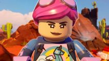 A Fortnite Lego character with pink hair has a determined look as she searches for Lego Fortnite flexwood on a backdrop of the desert biome.
