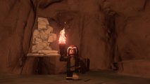 Lego Rogue standing in front of a Lego Fortnite marble vein inside a cave. She's holding a torch to light the room.