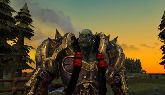 Image of an green-skinned orc warrior in golden plated armor standing in a war torn field at dawn.