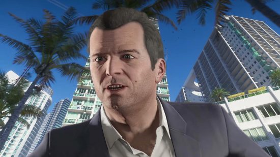A man, his head and shoulders visible, in front of a palm trees and buildings.