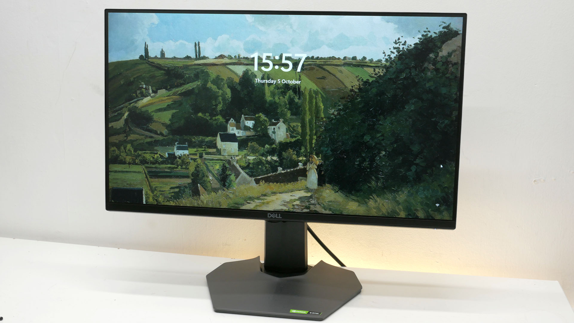 Dell G2524H review image showing the front of the monitor with the screensaver visible behind the time.
