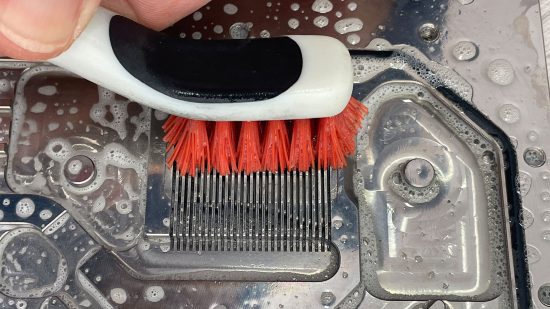 Someone cleans a PC cooling waterblock using a brush