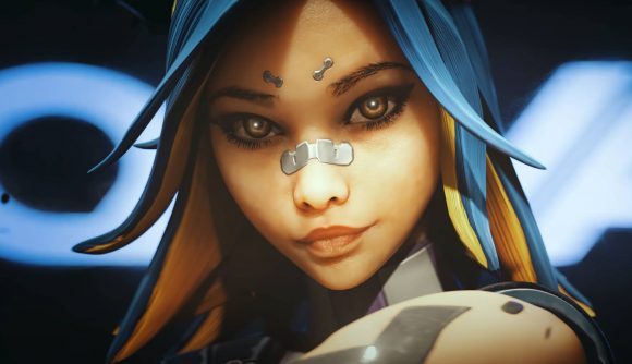 New Valorant patch notes finally add the only skins we ever wanted: A pretty woman with blue and yellow hair and glowing amber eyes with a plaster across her nose looks into the camera smirking