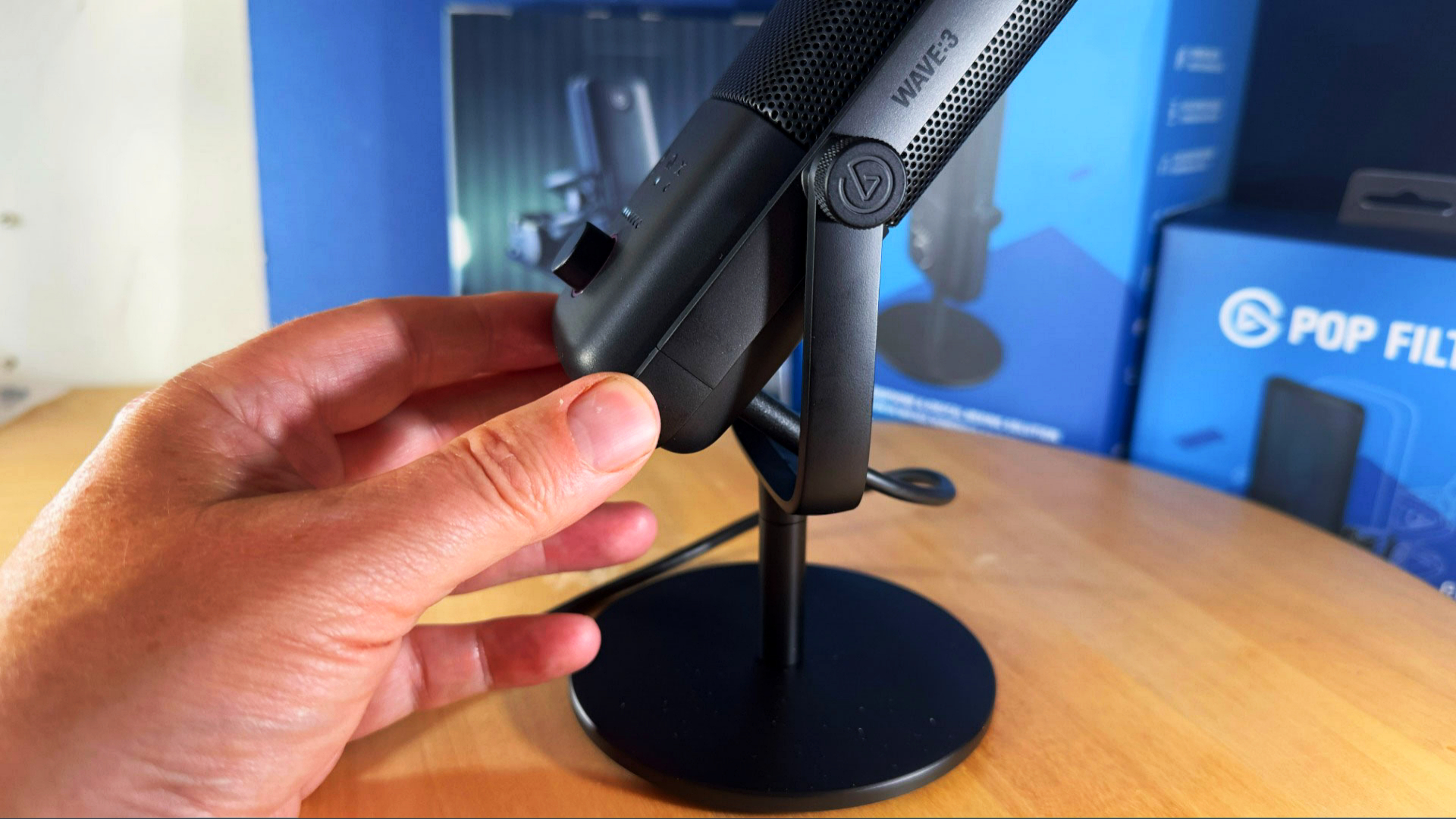 Elgato Wave:3 review image showing a human hand tilting the mic stand.