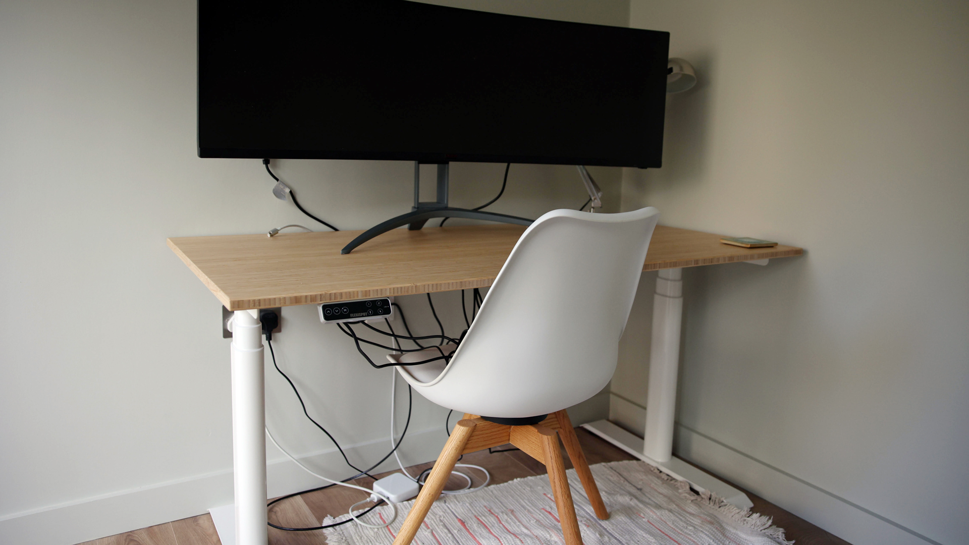 Flexispot E8 Standing Desk review image showing the desk from a diagonal angle with a monitor on it and a chair set up.