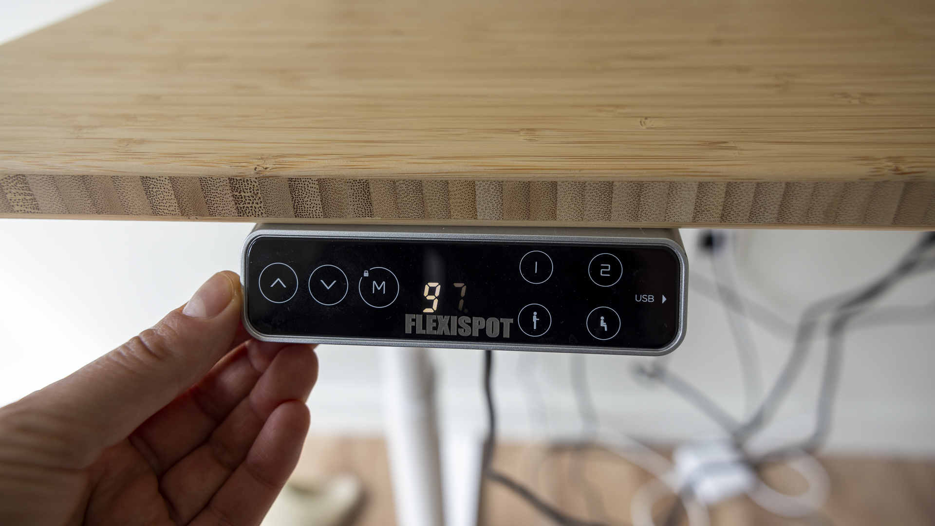 Flexispot E8 Standing Desk review image showing the USB panel's screen near a human hand.