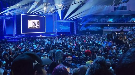 The crowd sit bathed in blue waiting for the start of BlizzCon 2023.
