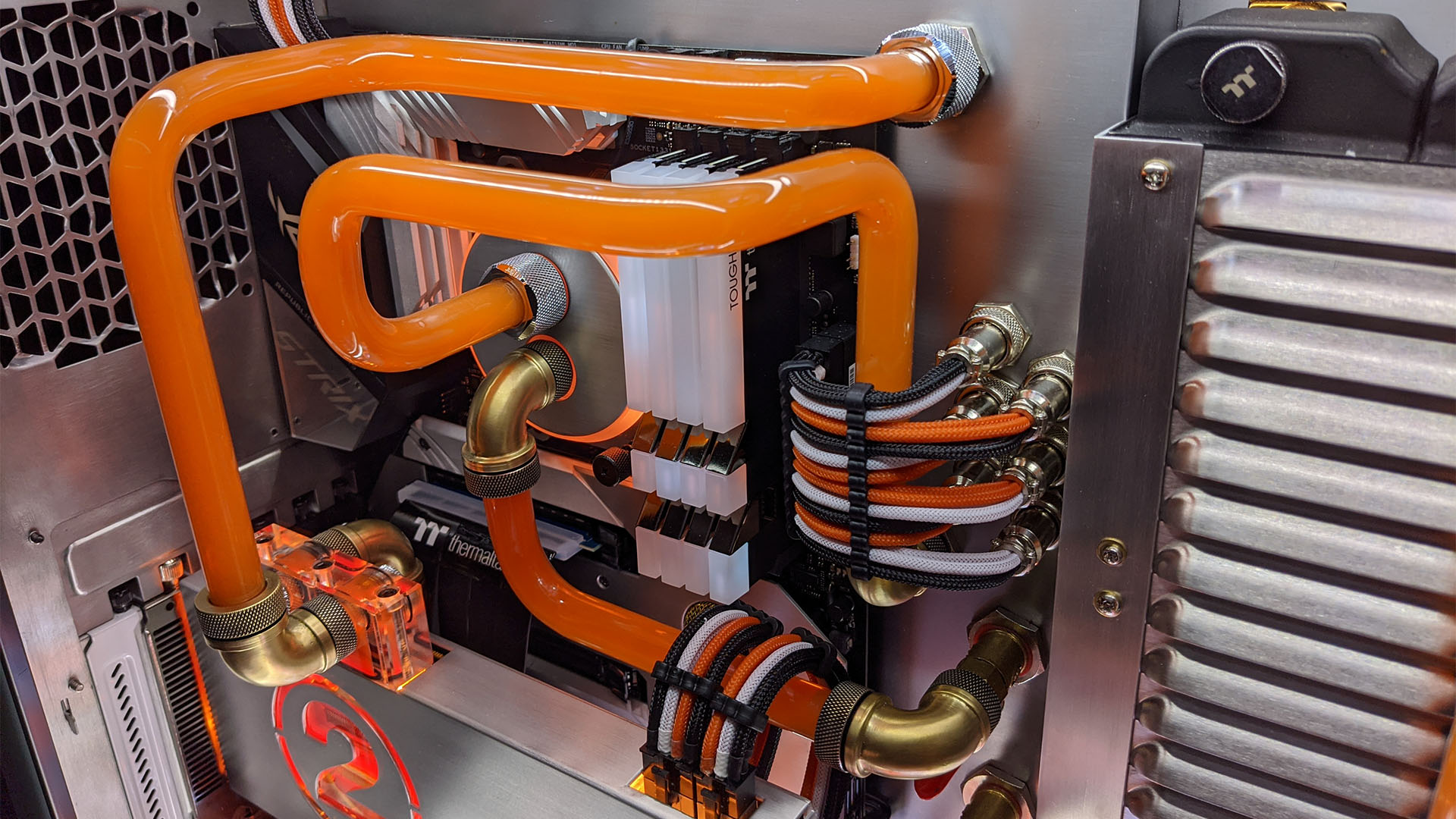 The gaming PC with brass fittings on orange water cooling pipes