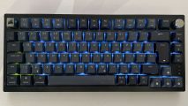 A top down image of the Corsair K65 Plus Wireless with faint blue and green rgb lighting behind the keys
