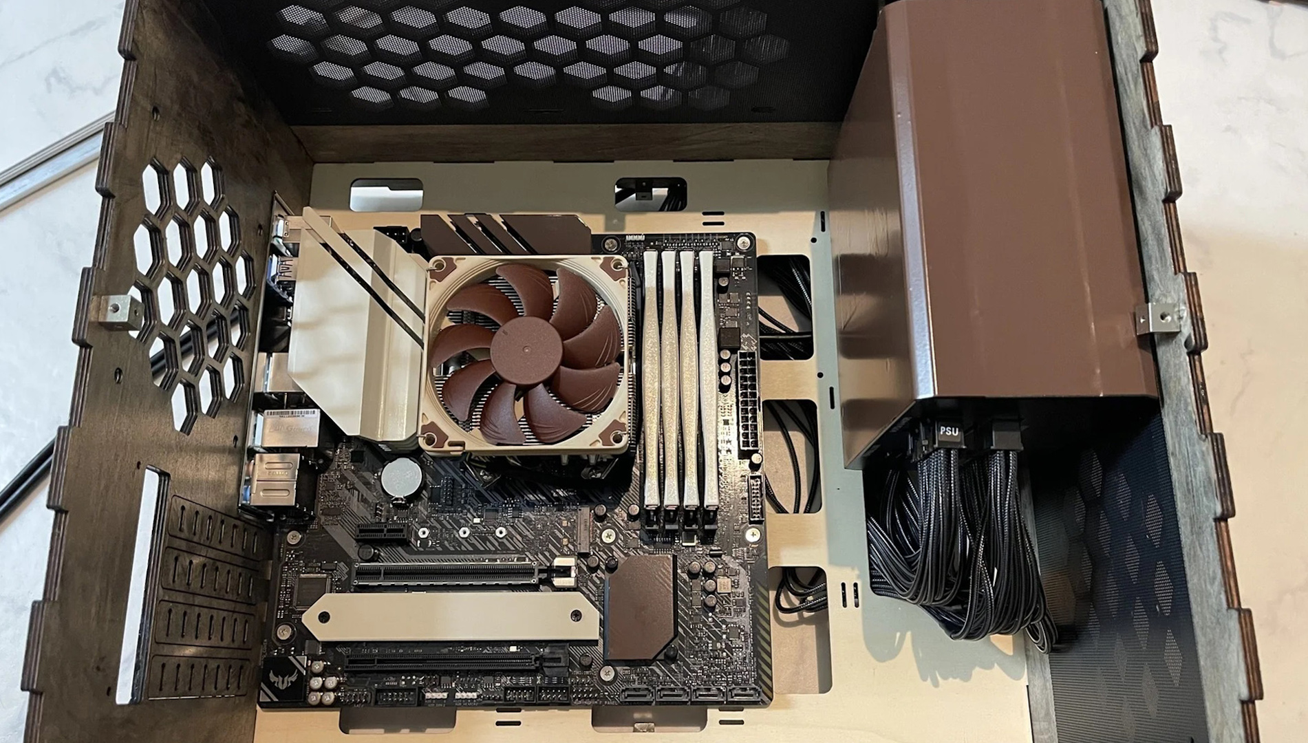 The inside of the wooden Noctua gaming PC with painted motherboard and PSU shroud