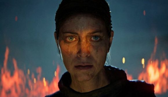 Senua stares ahead of her as a fire rages around her in Hellblade 2.