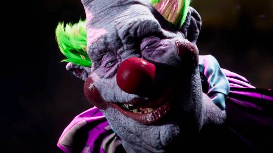 A creepy clown with green tufted hair and a huge red nose grins menacingly into the camera