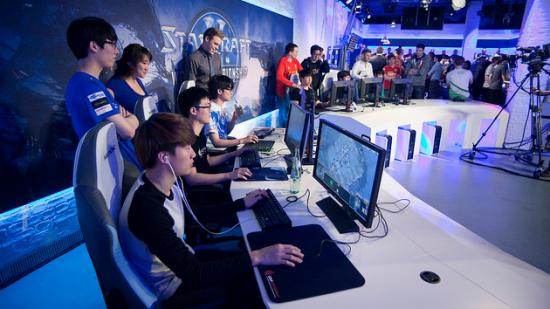 The casters and pros of North American and European StarCraft arrayed in a row around desktop PCs.