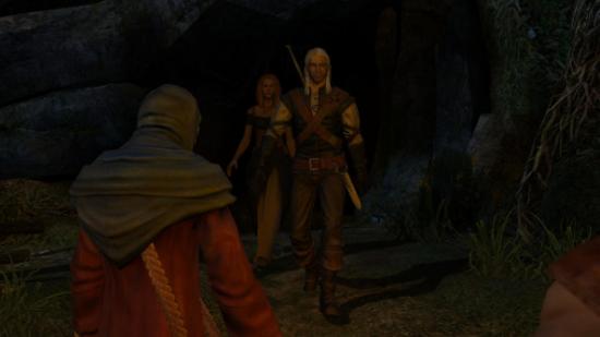 The silver-haired Geralt strides down a cave tunnel entrance to face a medieval mob lit by torchlight.