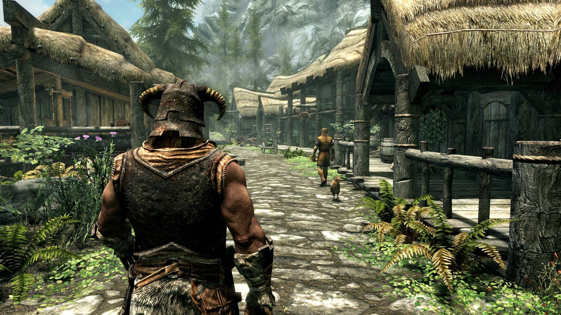 Best open-world games: the Dovakin, wearing a horned helmet and leather armour, is walking down a cobbled path in a village.