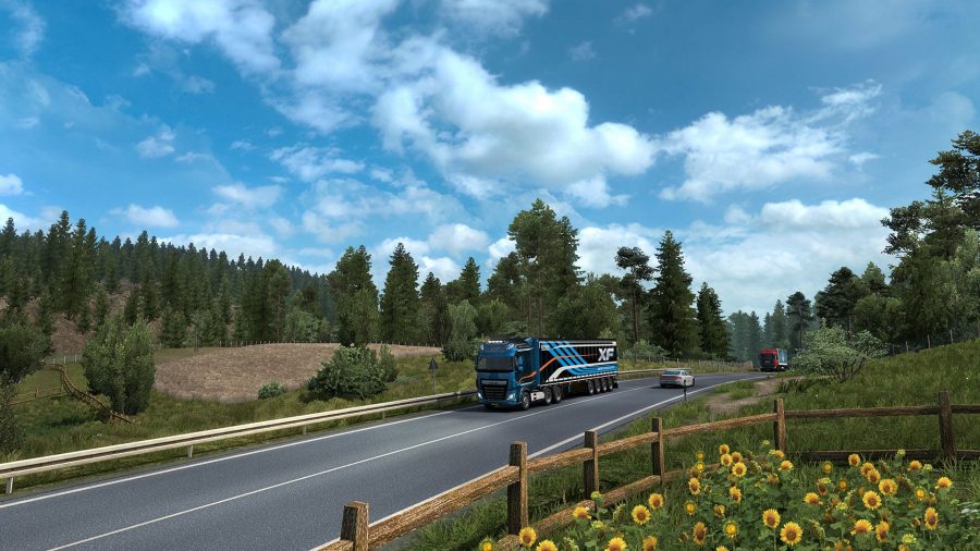 Un camion noir et bleu roulant le long d'une route de campagne
