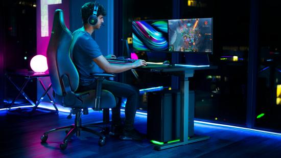 A man sits on the Razer Iskur gaming chair, playing Dota 2 with the logo on the screen for some reason
