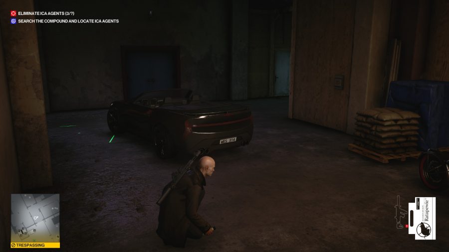 Agent 47 sneaking past a sports car in a dark warehouse in Hitman 3