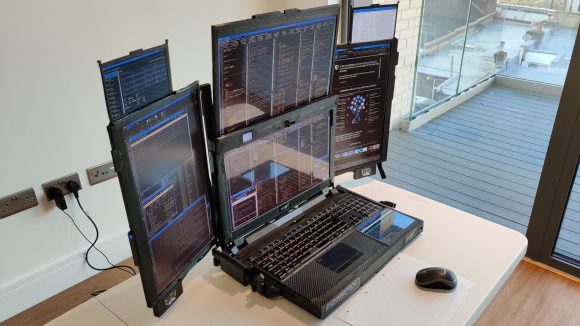 A black gaming laptop with seven screens has all its monitors extended