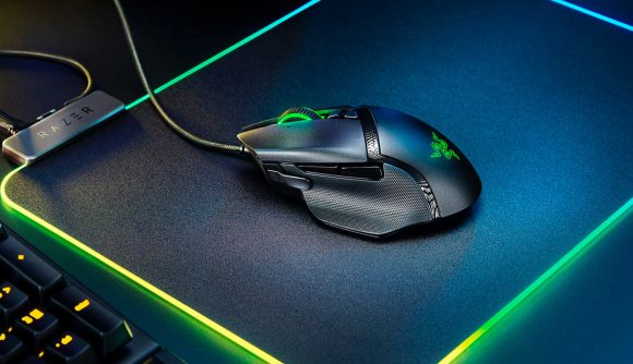 A black and green gaming mouse placed on a colourful RGB mouse mat