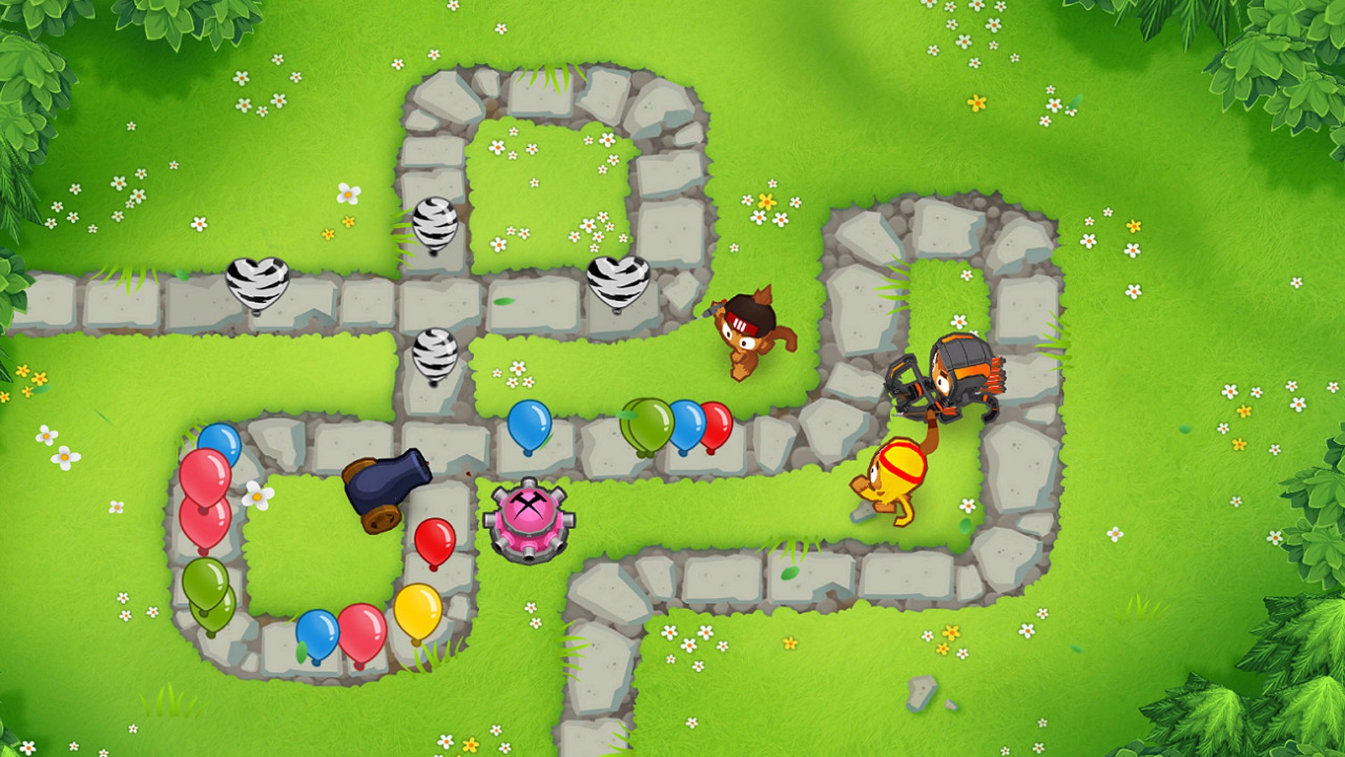 Best tower defense games: balloons make their way along a stone path in a grassy field, with turrets on in Bloons 6.