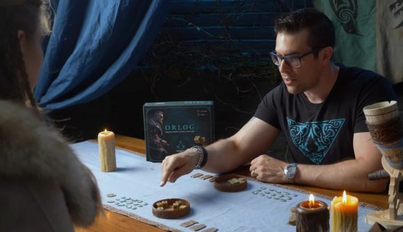 Two people sit at a table to play Orlog by candlelight
