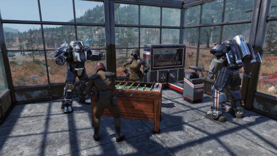 Members of the Brotherhood of Steel play foosball and arcade games in a brightly lit room looking out across the wilderness in Fallout 76