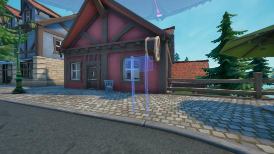 A light blue outline of a sign outside of a pink cottage in Fortnite