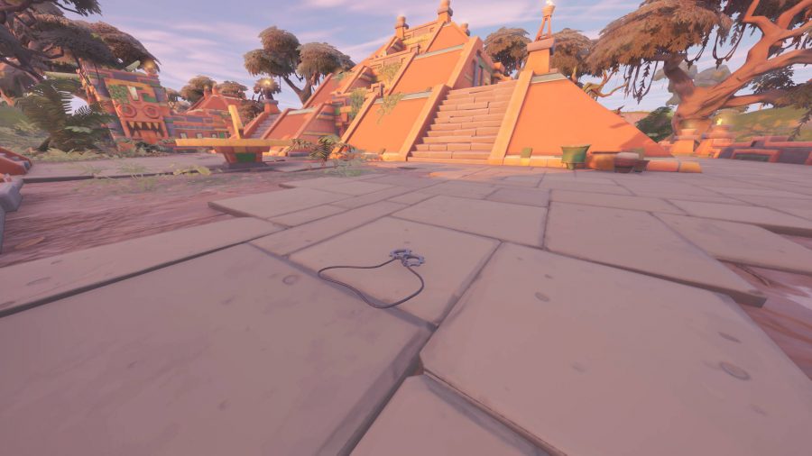 Some Cog tags resting on the ground in front of an Aztec pyramid in Fortnite.