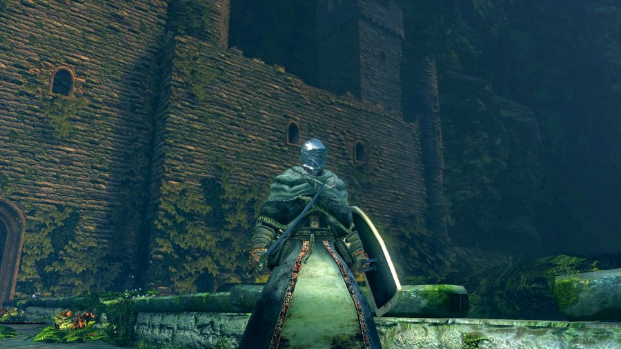 Un chevalier en armure se tient devant un château la nuit dans Dark Souls