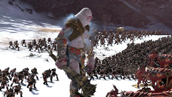 A massive giant lumbers into battle alongside formations of soldiers in the snowy wastes of Total War: Warhammer 3.