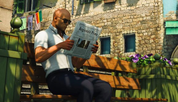 PCGamesN news writer 2022; Hitman's Agent 47 sits on a bench while reading a newspaper in a Spanish town