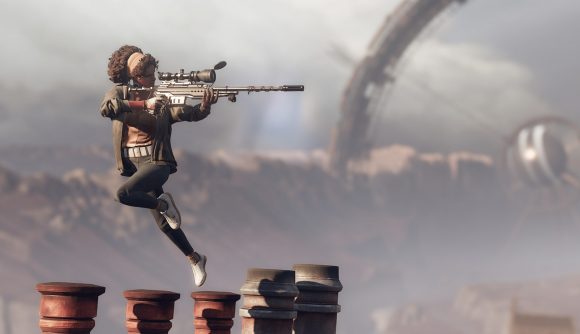 Julianna leaps while aiming a sniper rifle in Deathloop. Behind her, the massive circular array that creates the time loop can be seen poking over a mountain ridge.