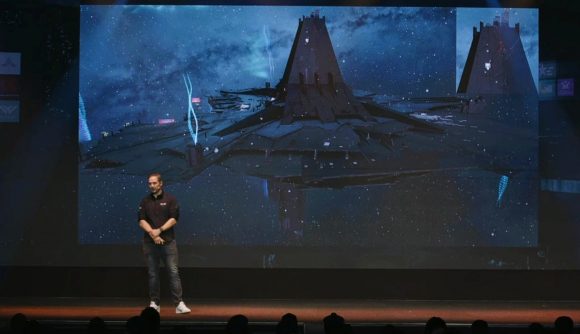 Snorri "CCP Rattati" Árnason discusses Eve Online's new heraldry system during the Fanfest keynote in Reykjavik, as he stands in front of a giant screen displaying a space station with holographic projections emanating from several points along its rim