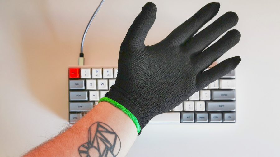 Razer Enki gaming chair included gloves worn by hand Infront of white keyboard 