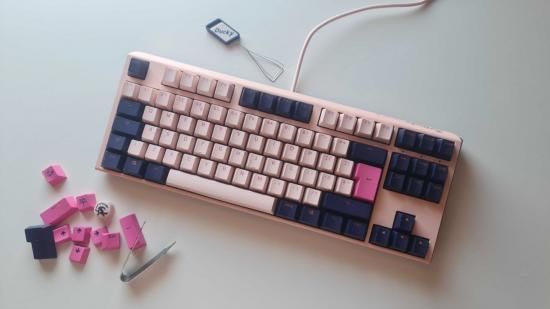 Ducky One 3 review - Fuji TKL edition: the pretty pink gaming keyboard lays on the desk next to its extra keycaps