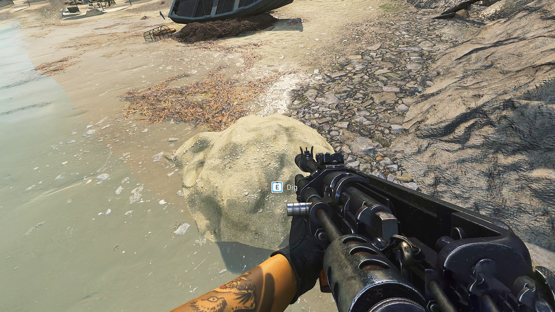 Call of Duty Warzone קבור מיקומי חפירי אוצר: מבט ראשון של מישהו מחזיק ברובה תקיפה תוך כדי התבוננות בתל חול על החוף