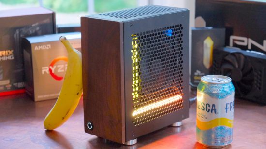 Small gaming PC with yellow LED lights inside sitting next to banana and soda can