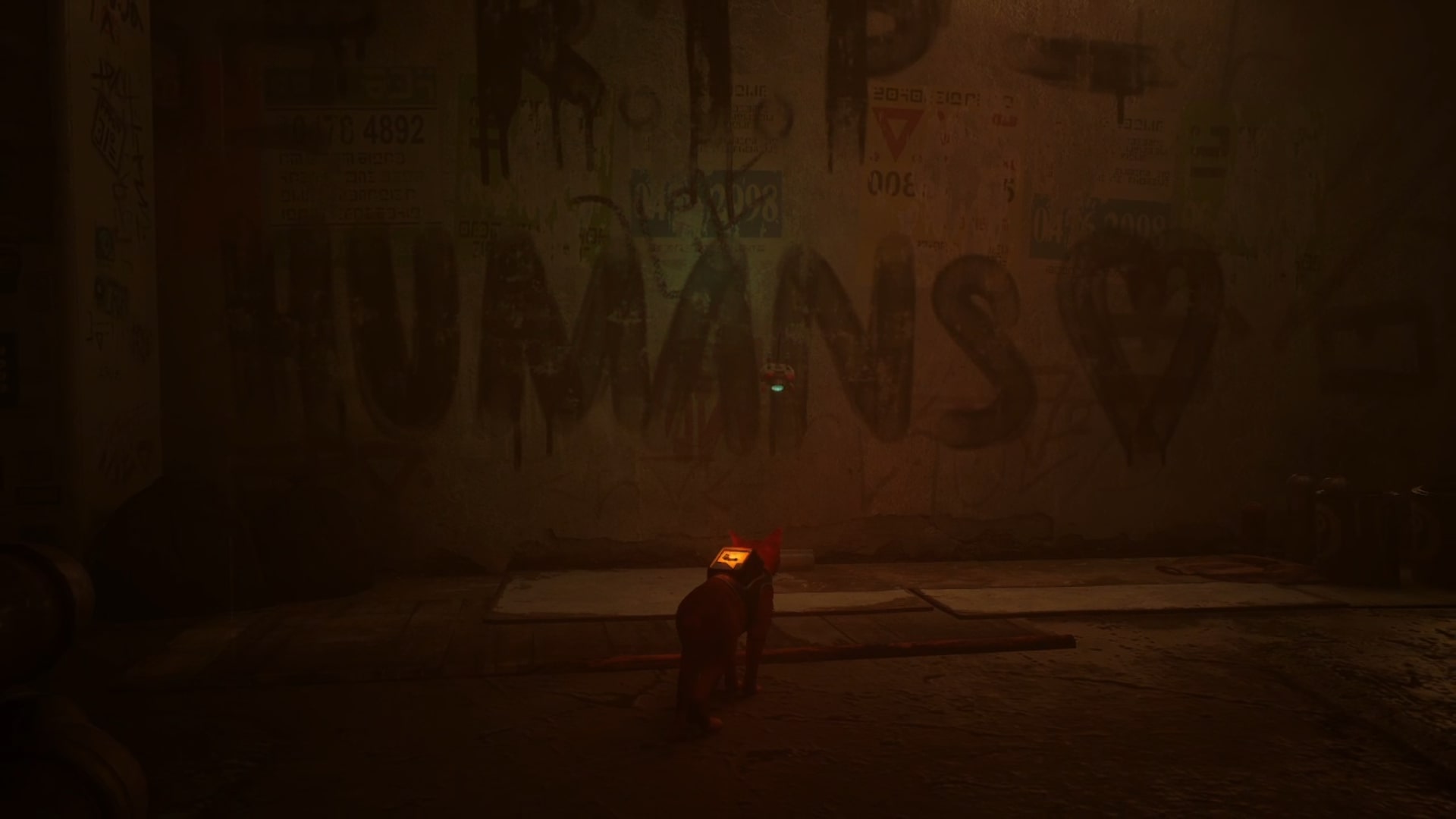 Stray memories guide: The RIP HUMANS <3 graffiti is emblazoned across a concrete wall that’s covered in faded posters for businesses once owned by humans