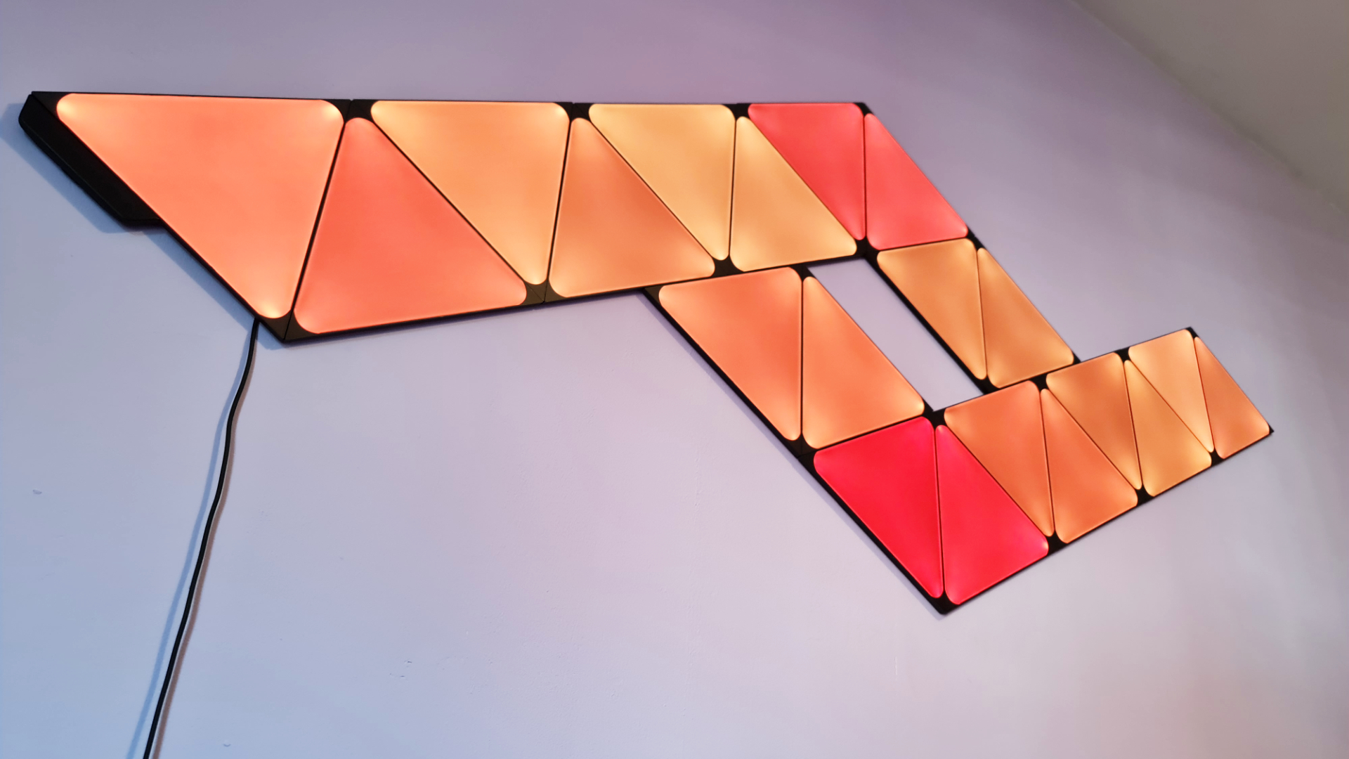 Nanoleaf Ultra Black Shapes with the traingles shining orange and red